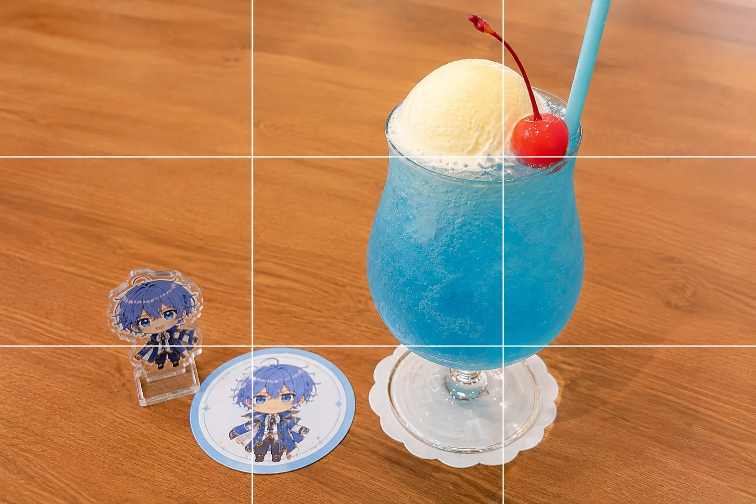 三分割法の作例。コラボカフェのテーブルで、特典コースターと同じキャラのアクスタを添えたコラボドリンクを交点に置いた構図イメージ。